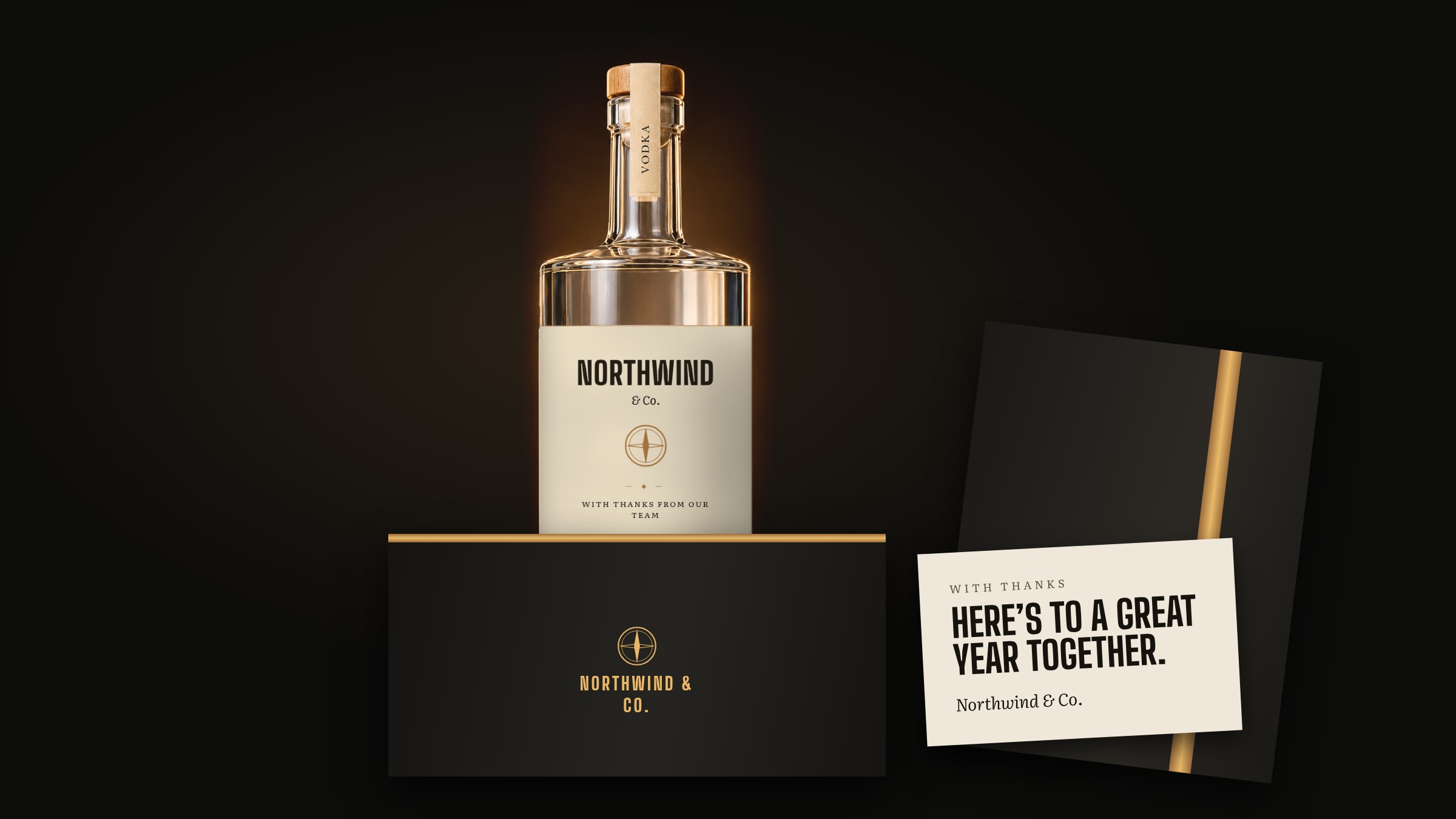 A whiskey bottle with a custom label beside a greeting card and a black gift box.